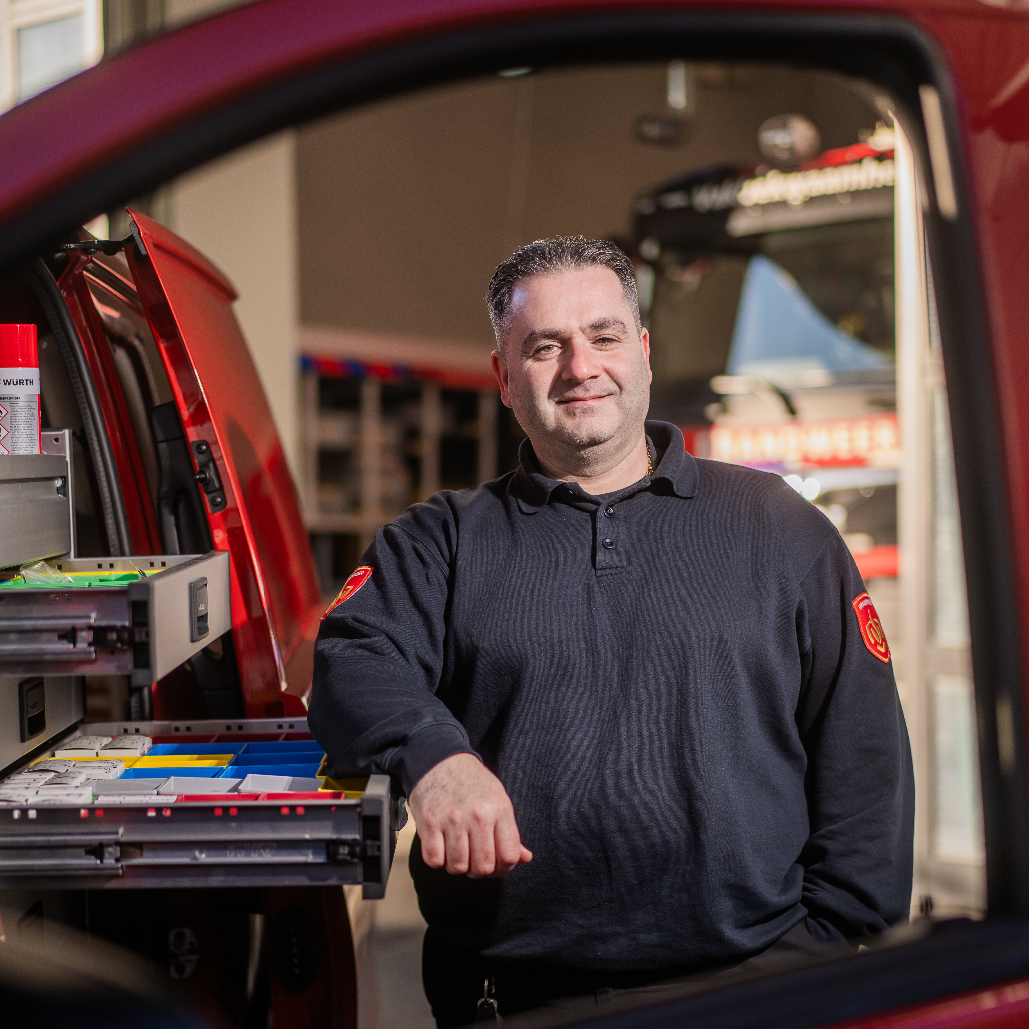 Hasim staat glimlachend naast brandweerauto