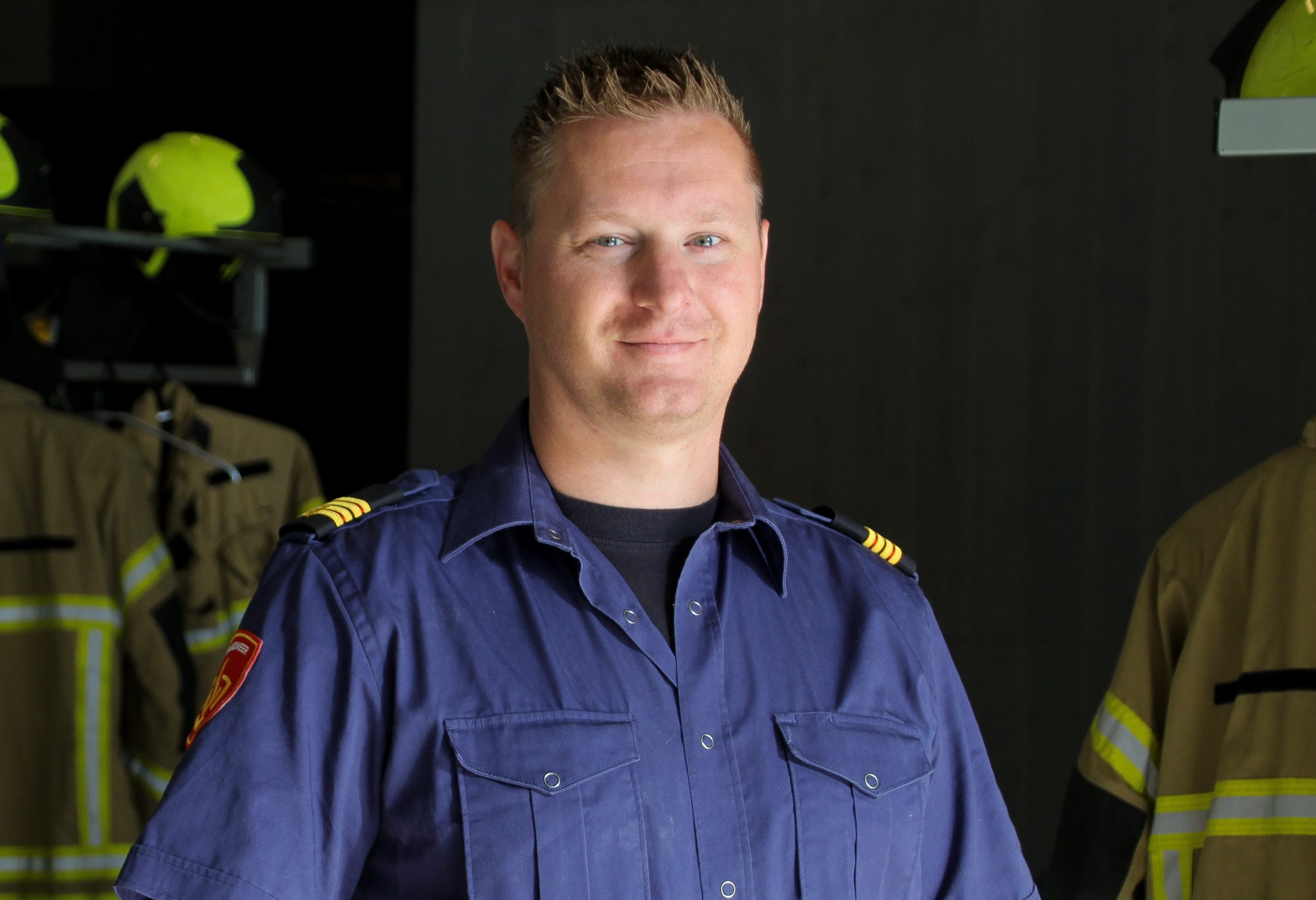 Brandweerman staat voor kazernekleding in de uitrukhal van de kazerne.