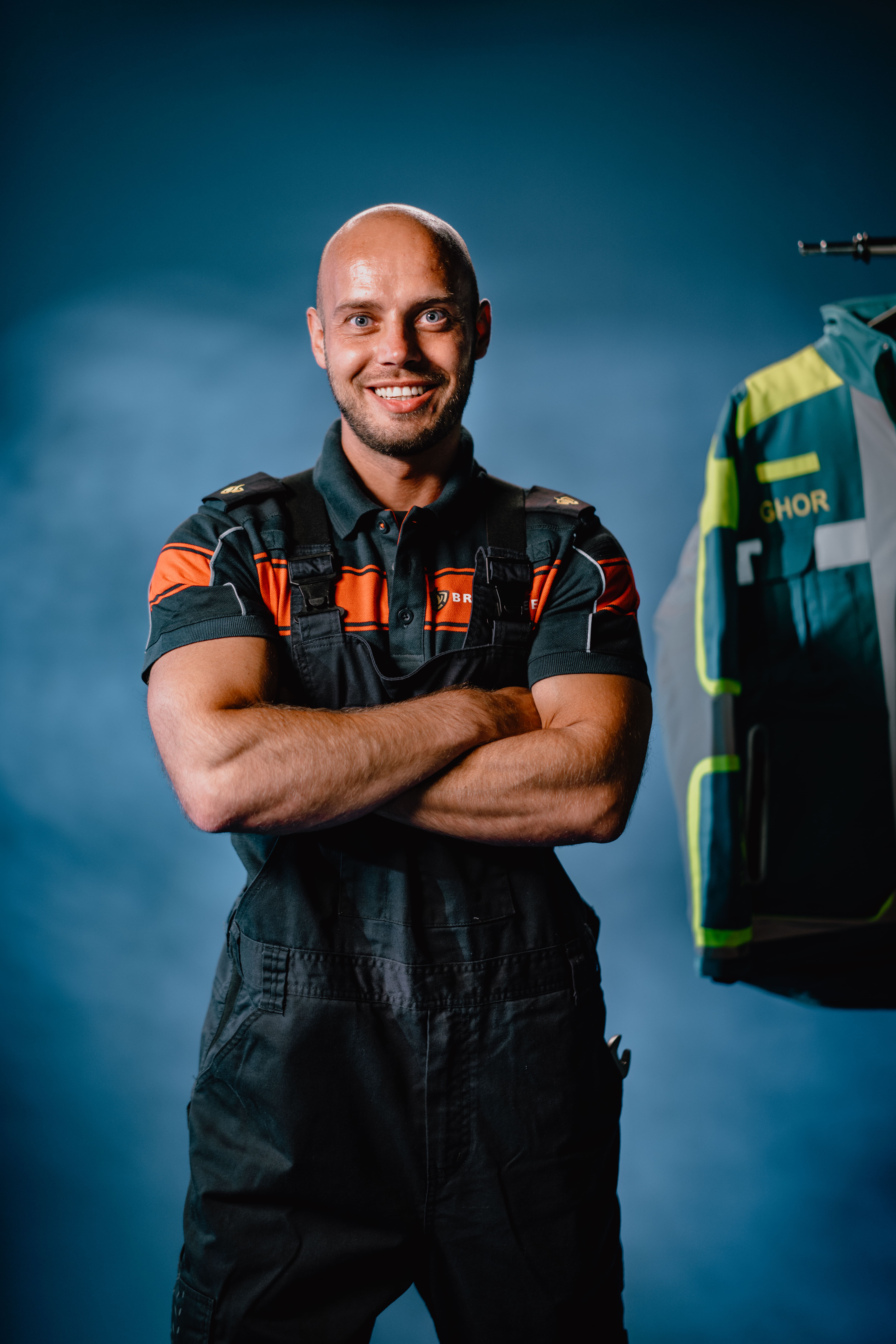 Lachende monteur in overall met over elkaar geslagen armen