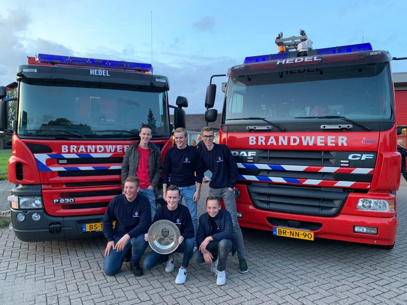 Jeugdbrandweer poseert met kampioensschaal voor tankautospuiten