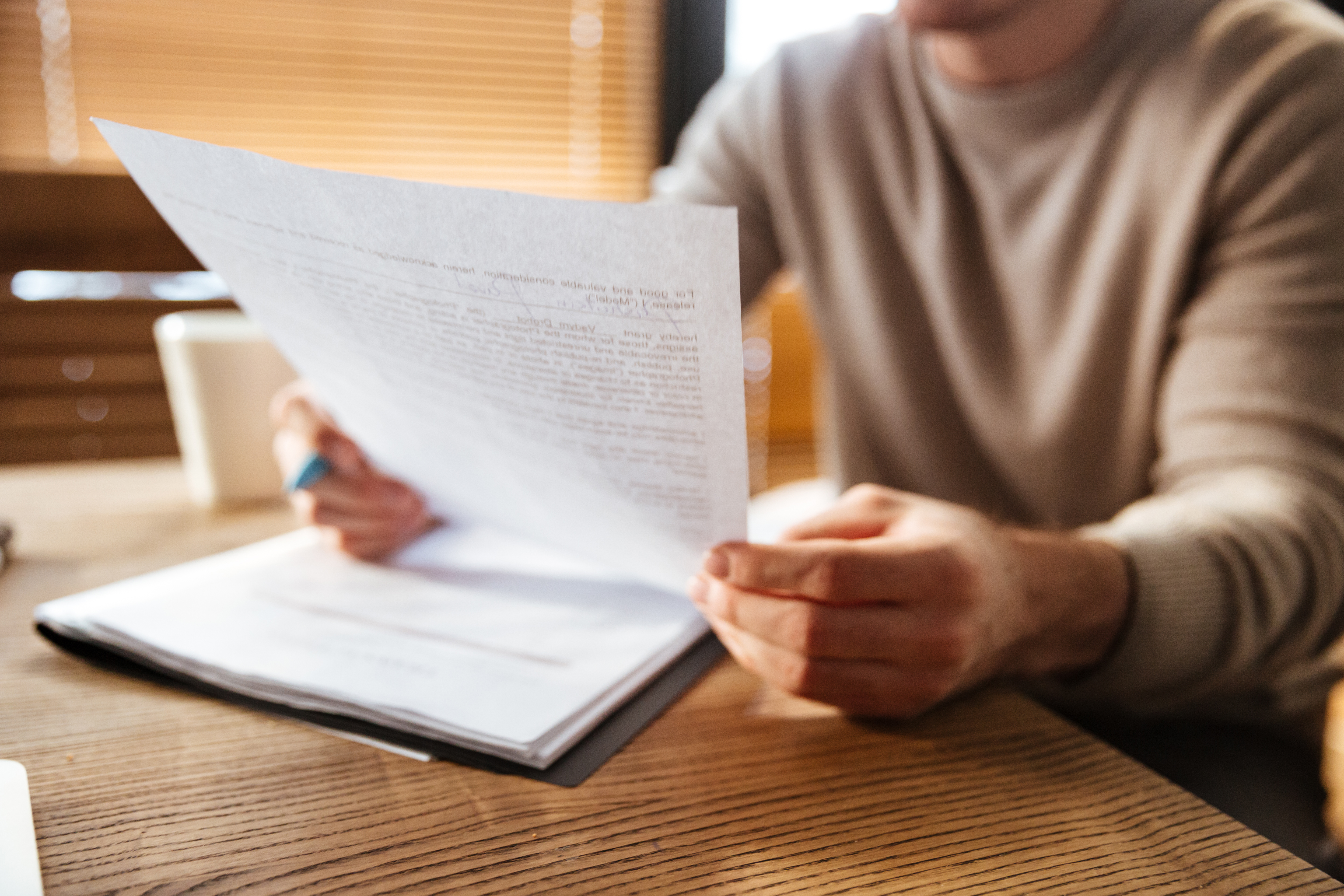 Man leest uitgeprint document aan tafel