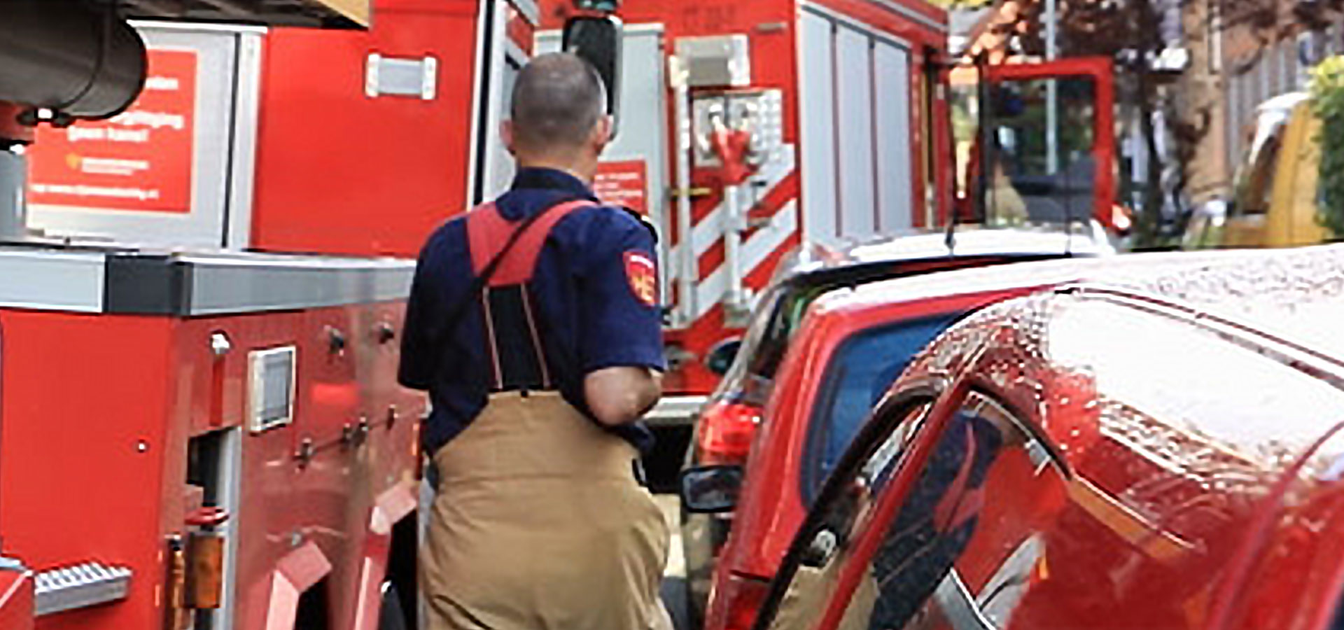 Brandweerman loopt tussen brandweervoertuigen en auto's door