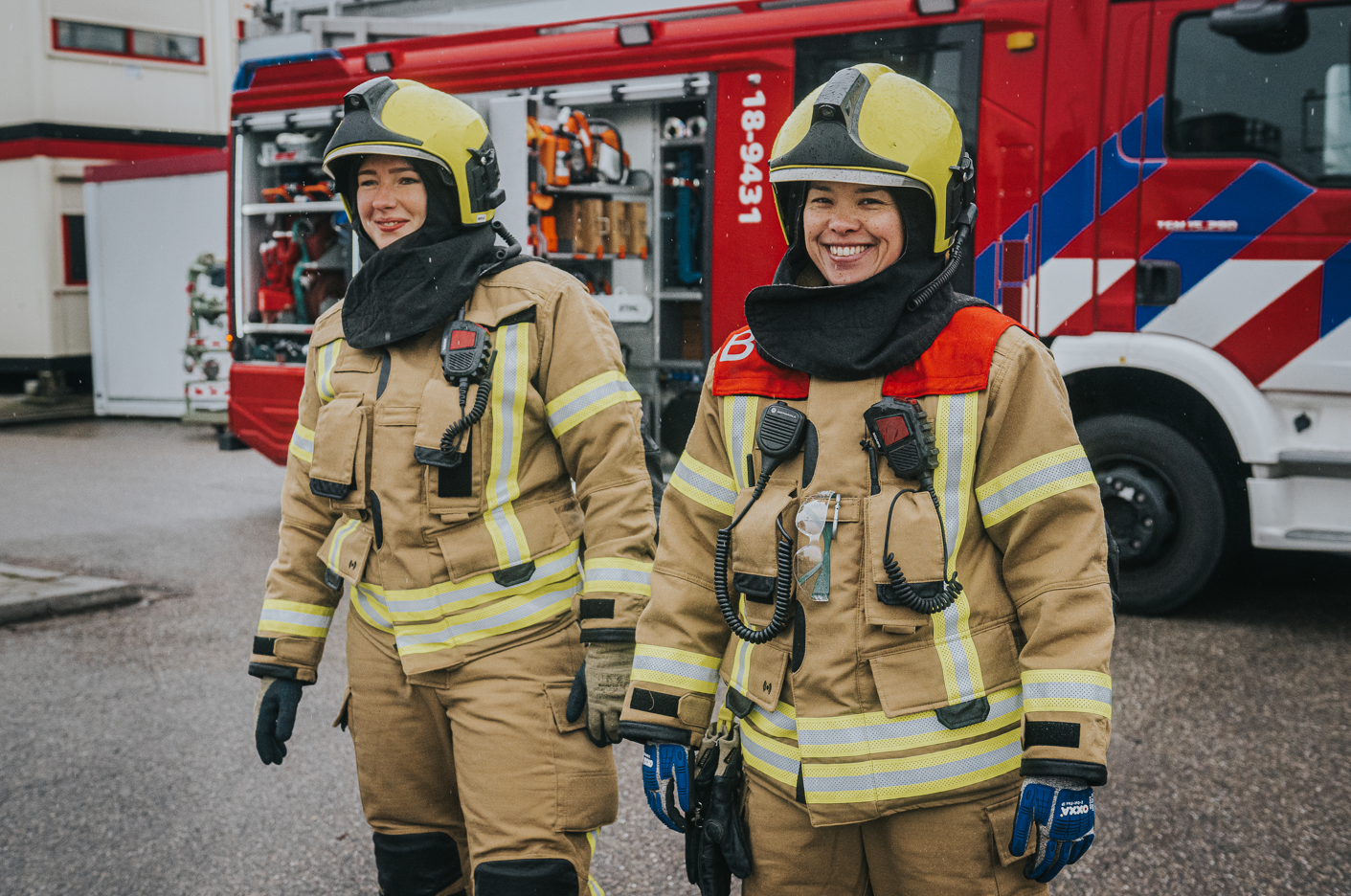 Twee brandweervrouwen in incidentkleding voor brandweerauto