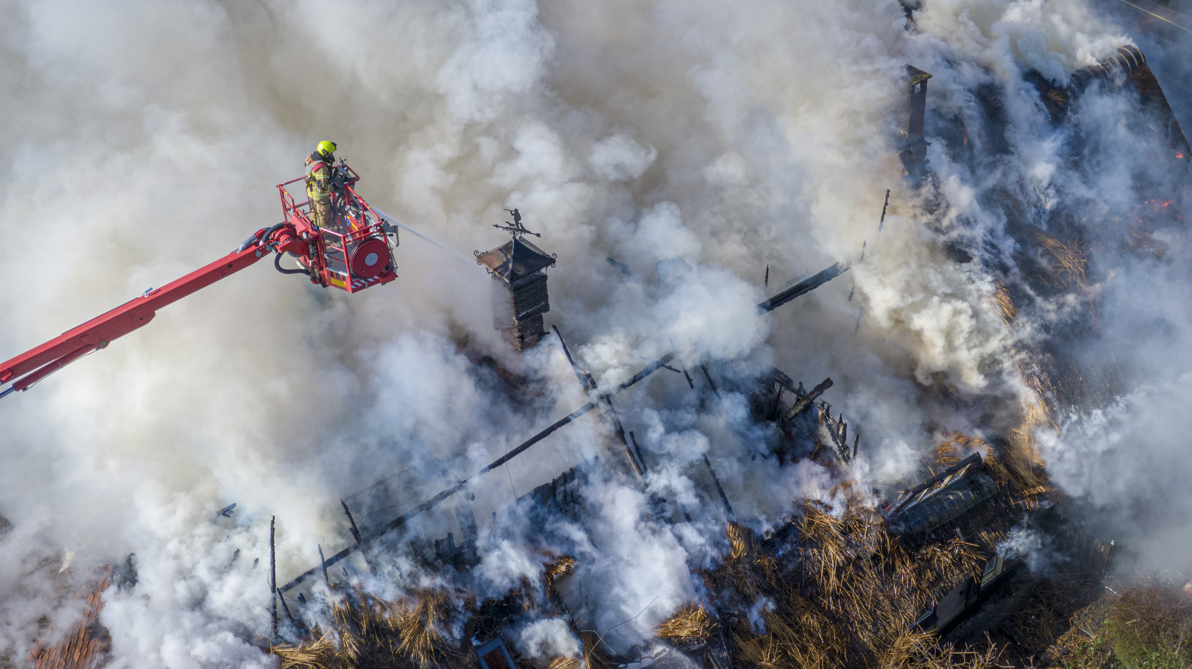 Brandweerman die vanuit de lucht brandend huis aan het blussen is.