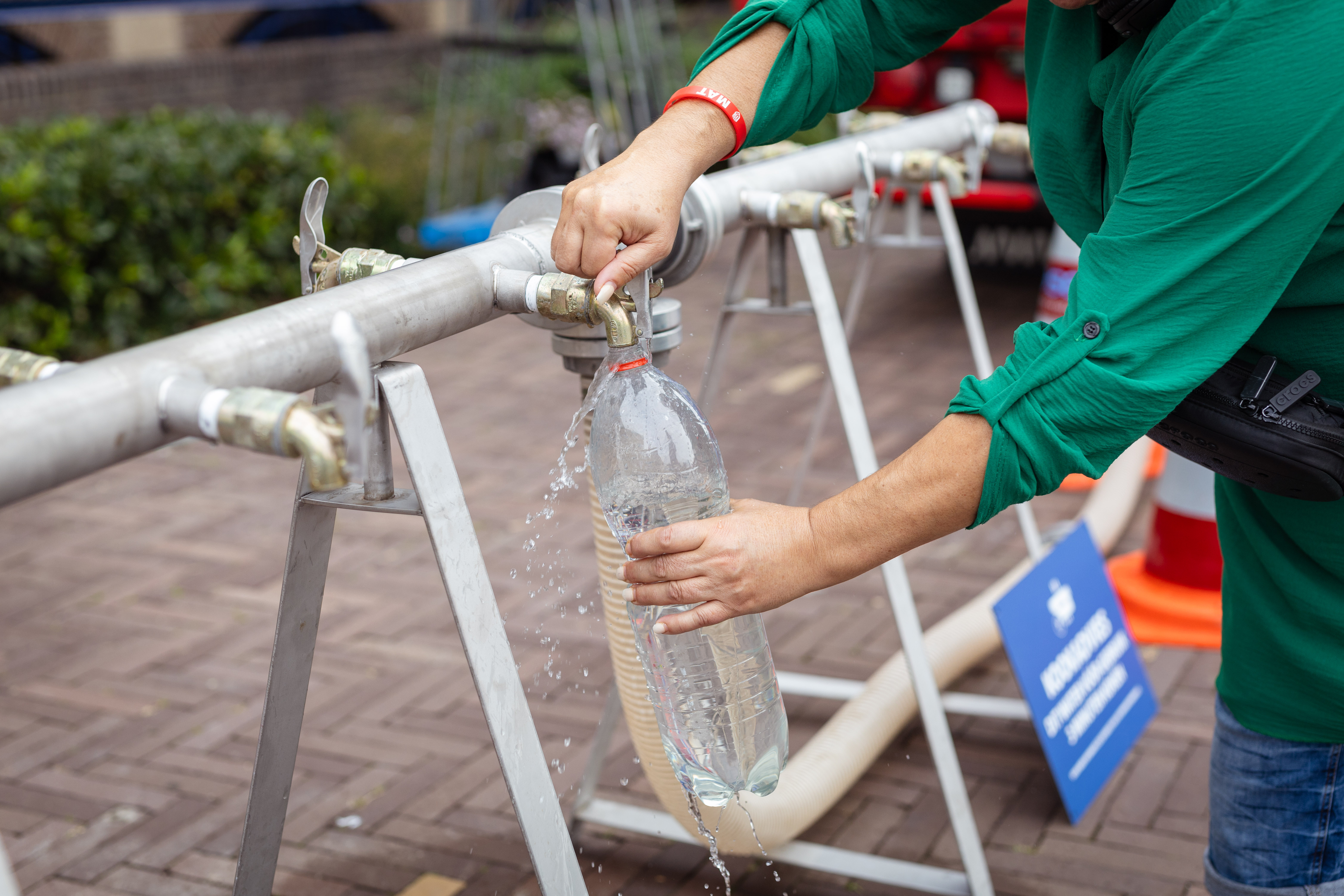 Inwoner haalt water uit de kraan van het nooddrinkwaterpunt