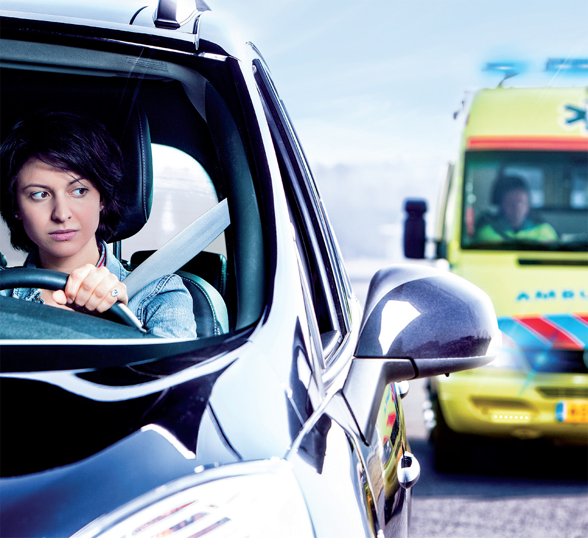 Vrouw kijkt in zijspiegel naar naderende ambulance