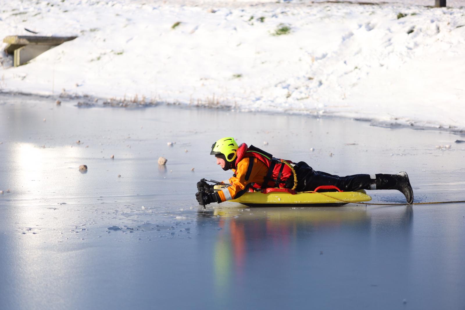 Reddingswerken op plank op het ijs