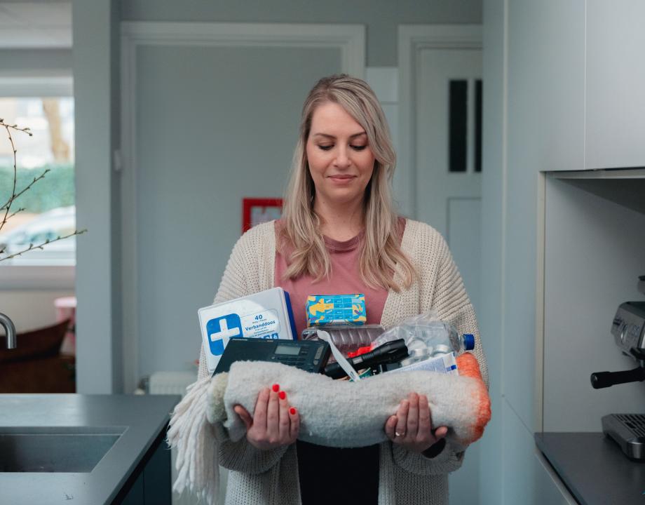 Vrouw met de inhoud van een noodpakket in haar handen